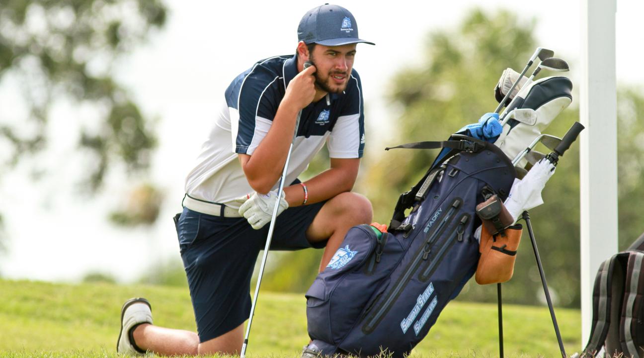 Student on a golf course with golf clubs