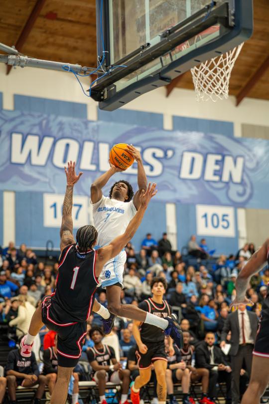 Student jumping in the air with a basketball 