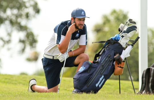 Student on a golf course with golf clubs